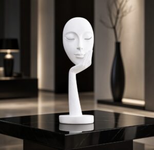 White resin mask ornament of a lady with her head in her hand on a dark wood table.