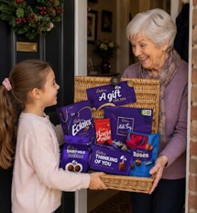 Child giving her grandmother a Cadbury gift basket at the front door
