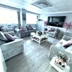 Room with silver crushed velvet sofas forming a square with square coffee table to the centre.