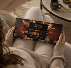 Small box of Green & Blacks chocolates on woman's lap